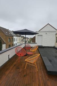 three chairs and an umbrella on a deck at Stylish flat with rooftop in Ixelles in Brussels