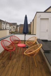 three chairs and a table and an umbrella on a deck at Stylish flat with rooftop in Ixelles in Brussels