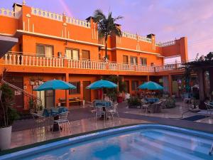 a hotel with a pool and tables and umbrellas at Pousada Krolow in Pelotas