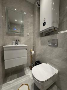 a bathroom with a white toilet and a sink at Desire Luxury Apartment with private garage in Varna City