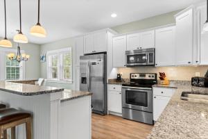 a kitchen with white cabinets and stainless steel appliances at Bay Breeze in Kill Devil Hills +23 photos