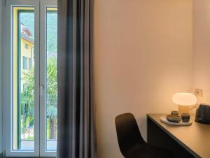 a room with a desk with a lamp and a window at Urban Living in Como