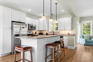 a kitchen with white cabinets and bar stools at Bay Breeze in Kill Devil Hills