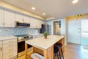 una cocina con armarios blancos y una isla con mesa en Sea Colony --- 204 N Edgewater, en Bethany Beach