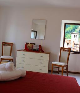 ein Schlafzimmer mit einer Kommode, 2 Stühlen und einem Spiegel in der Unterkunft La Piazzetta in Menaggio