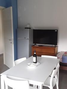 a bottle of wine sitting on a white table with a television at Il Tuffatore in Capaccio-Paestum