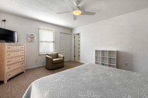 Un dormitorio con una cama, un televisor y una silla. en Beach Bound, en Southern Shores
