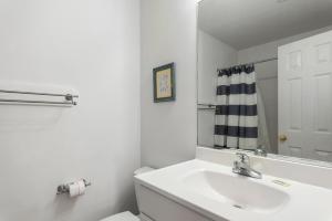 Un baño blanco con lavabo y espejo. en Beach Bound, en Southern Shores