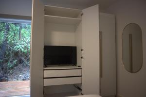 a living room with a tv and a cabinet at White Haus 2 - Rainforest heaven close to beaches in Ucluelet