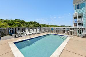 a swimming pool with chairs and a fence at Carolinian in Nags Head