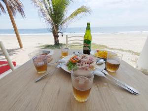 a table with a plate of food and drinks on the beach at Bungalows Pascana 58 in Canoas de Punta Sal