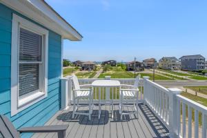 a balcony with a table and chairs on a blue house at Carolinian in Nags Head