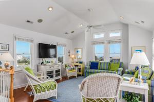 a living room with a couch and chairs and a tv at Carolinian in Nags Head