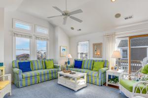 a living room with blue and green furniture and windows at Carolinian in Nags Head +27 photos