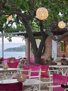 a patio with tables and chairs and a tree at Maniatis Garden in Achladies
