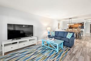 Una sala de estar con un sofá azul y un televisor. en Heron Cove, en Nags Head