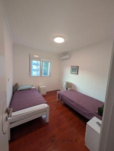 two beds in a room with wooden floors at Penthouse NIKOLA in Budva