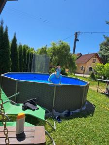 a boy sitting in a swimming pool in a yard at Ranč pod Hájom in Bobrovec