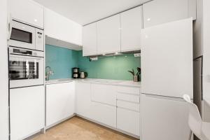 a white kitchen with white cabinets and green walls at Apartment Holiday Haven in Punta Prima