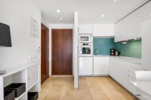 a kitchen with white cabinets and a wooden door at Apartment Holiday Haven in Punta Prima