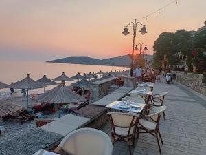 a row of tables and chairs on a beach at sunset at Petra Mare in Qeparo