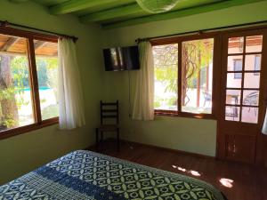 a bedroom with a bed and windows in a room at Hostal El Carmen de Pirque in Pirque