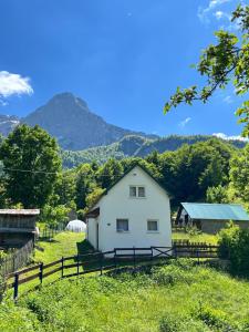 a white house in a field with mountains in the background at MAGLIC in Plužine