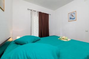 ein Schlafzimmer mit einem Bett mit blauen Laken und einem Fenster in der Unterkunft Apartments Toni in Banjol