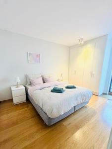 a white bedroom with a large bed and wooden floors at Tjuvholmen apartment 2BR in Oslo