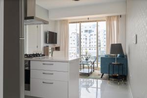 a kitchen with white cabinets and a living room at JR 7 Suites by Yellowkey in Santo Domingo