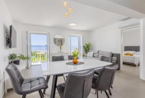 a white dining room with a white table and chairs at Apartments Amfora 2 in Podgora +26 photos