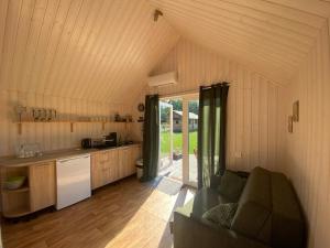 a kitchen and a living room with a couch in a room at Cabin for Seaside Retreat in Ķesterciems