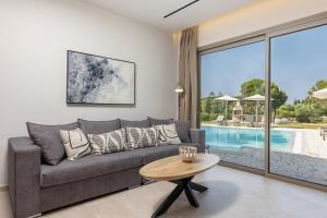 a living room with a couch and a table and a pool at Villa Ismini Periyali in Vasilikos +31 photos