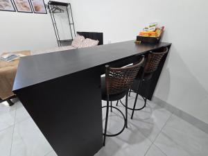 a black counter with two bar stools in a room at Flat completo a 21 minutos da BR-153 in Aparecida de Goiania