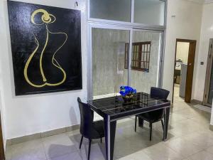 a dining room table with chairs and a painting on the wall at Apartment in Hadja Residence in Dakan