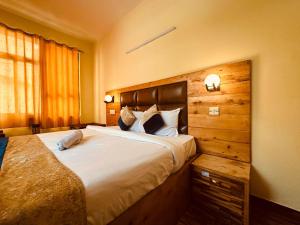 a bedroom with a large bed with a wooden headboard at Hotel Mist Bhimtal in Bhīm Tāl