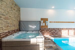 a hot tub in a room next to a pool at La Belle Hermine in Tonquédec