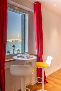 a table and a chair in front of a window at 3 Windows on St Mark - Waterfront Apartment in Venice