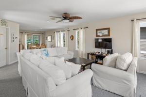 a living room with white couches and a tv at Corolla & Lime in Corolla