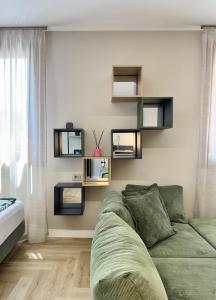 a living room with a green couch and shelves at Valcamonica Apartments - Mountain in Boario Terme +37 photos
