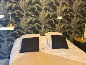 a bed with two pillows in a bedroom with a wallpaper at Studio proche aéroport de Nantes in Saint-Aignan-Grand-Lieu +4 photos