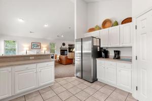 a kitchen with white cabinets and a stainless steel refrigerator at Country Roads in Corolla +51 photos
