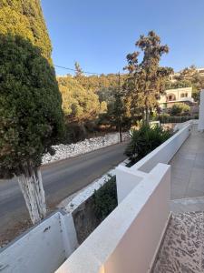 a white fence next to a road with trees at Fotinis Apartment in Kalymnos +2 photos