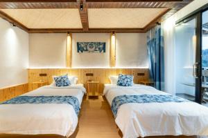 雷山县Xijiang Longtang Liyuan Mountain Resort B&B的配有窗户的客房内的两张床
