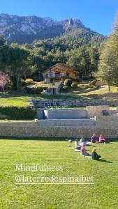 a group of people sitting on the grass in a field at La Torre d' Espinalbet in Castellar del Riu