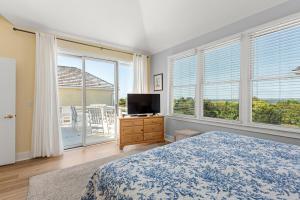 a bedroom with a bed and a tv and windows at Craven Haven in Nags Head +31 photos