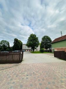 a brick driveway with a wooden fence and a building at Rožu namu apartamenti 4 in Kuldīga