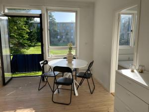 哥本哈根Charming apartment with easy access to central Copenhagen的有窗户的房间里有一张白色的桌子和几把椅子