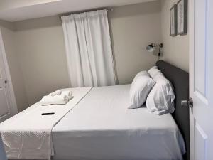 Haven 2 Bedroom by EWR airport في نيوآرك: غرفة نوم بها سرير مع ملاءات ووسائد بيضاء