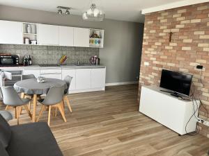 eine Küche und ein Wohnzimmer mit einem Tisch und einem TV in der Unterkunft Apartament MioMare, Basen, Parking in Kołobrzeg